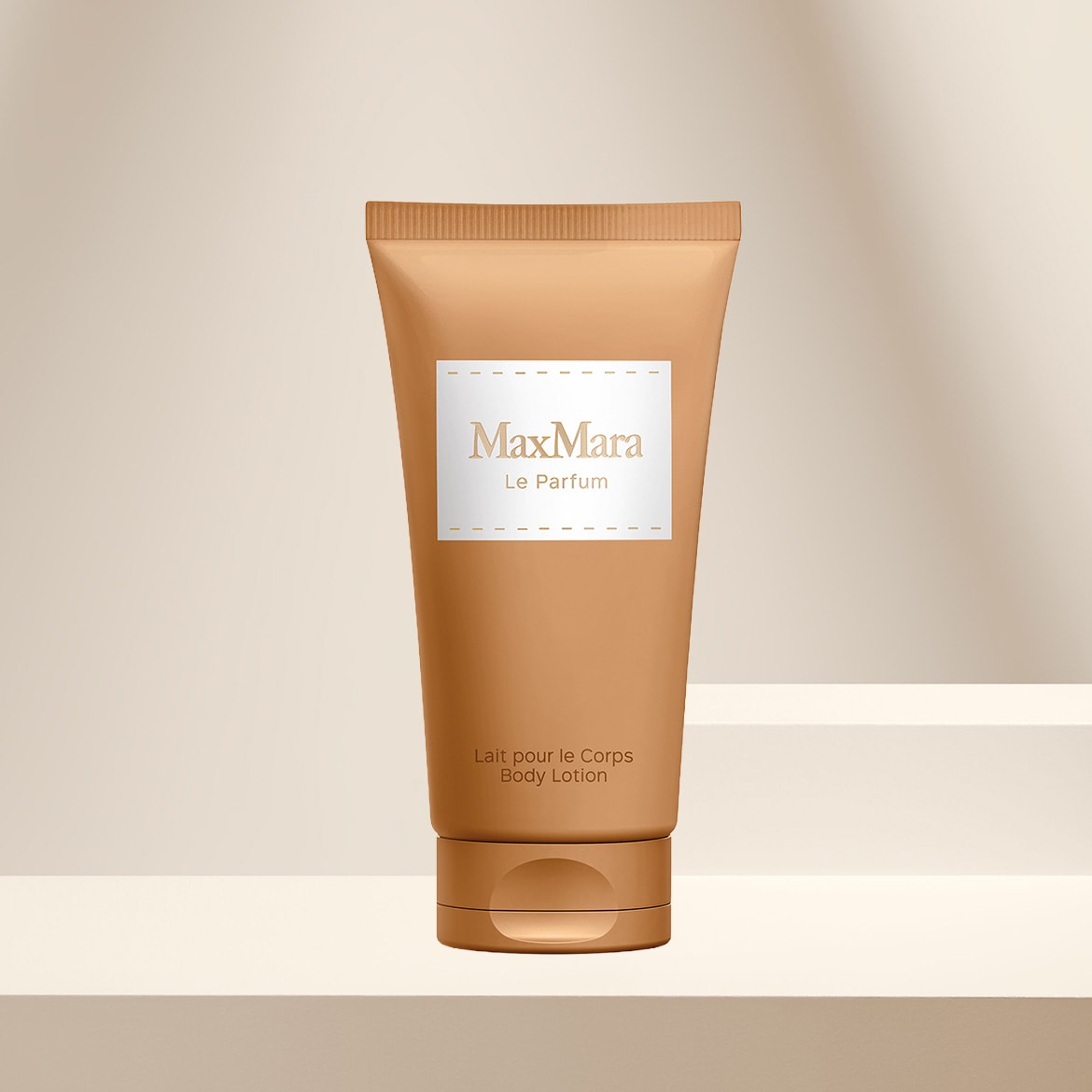 Die Max Mara Le Parfum Body Lotion in einer beigefarbenen Tube mit weißem Etikett und goldener Schrift steht auf einem hellbeigen Podest.