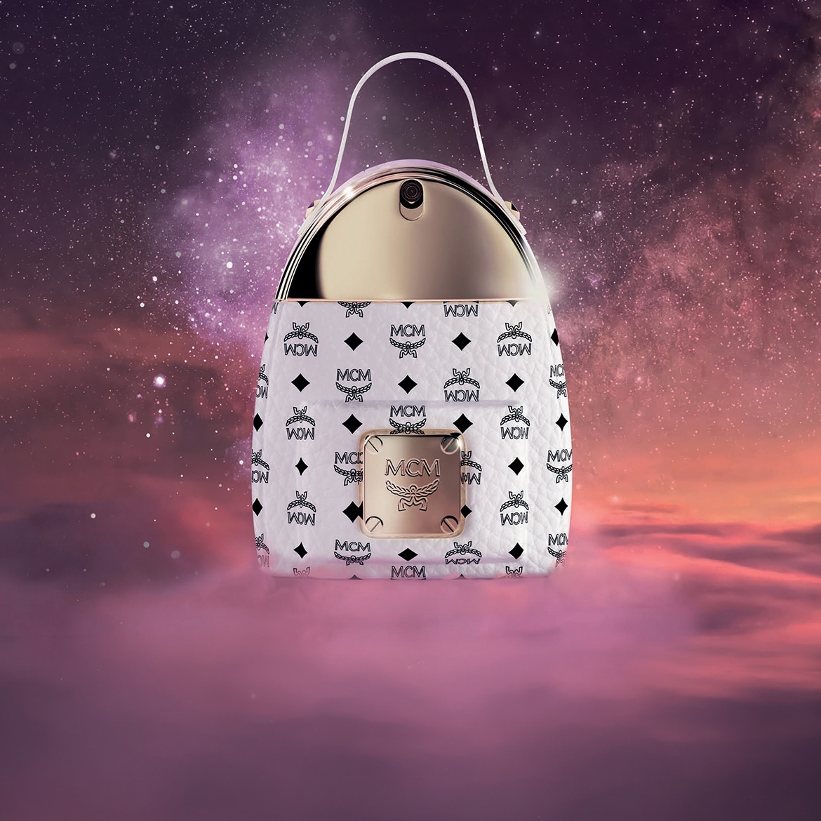 Der MCM Eau de Parfum Flakon ist wie eine weiße MCM-Handtasche geformt, mit einem goldenen Verschluss und Griff, vor einem lila-rosa Himmel mit Sternen.