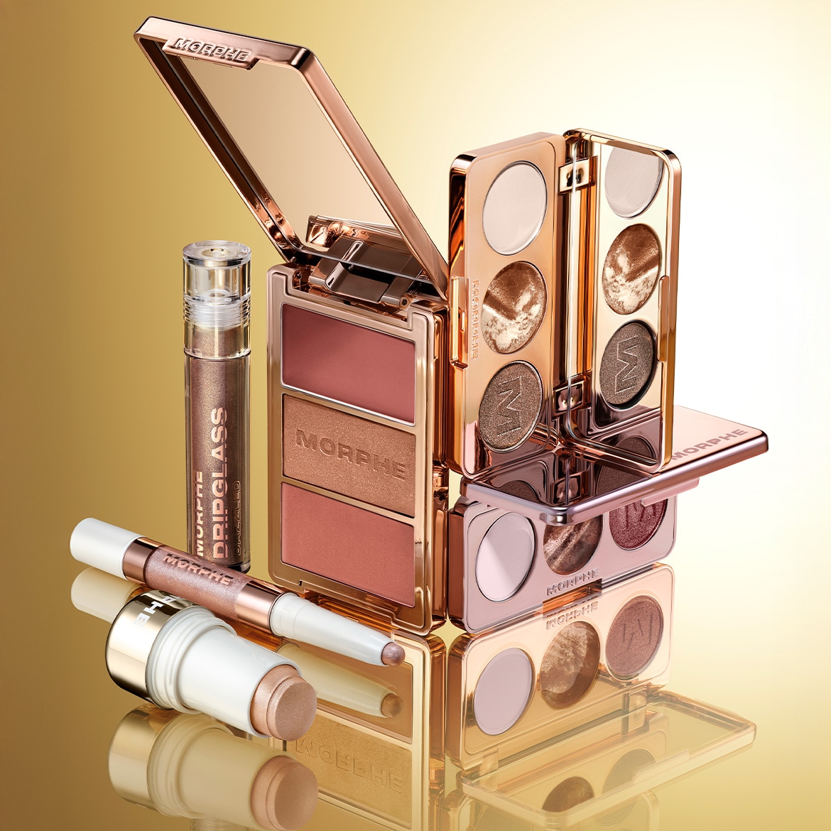 Nahaufnahme von Morphe Make-up-Produkten in Goldtönen, darunter Paletten, Lipgloss und ein Konturenstift, die auf einer glänzenden Oberfläche gestapelt sind.