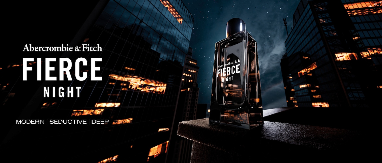 Das Abercrombie & Fitch Fierce Night Parfüm in einem eleganten, dunklen Flakon steht auf einem Mauervorsprung vor einer nächtlichen Skyline mit beleuchteten Hochhäusern und einem sternenklaren Himmel.