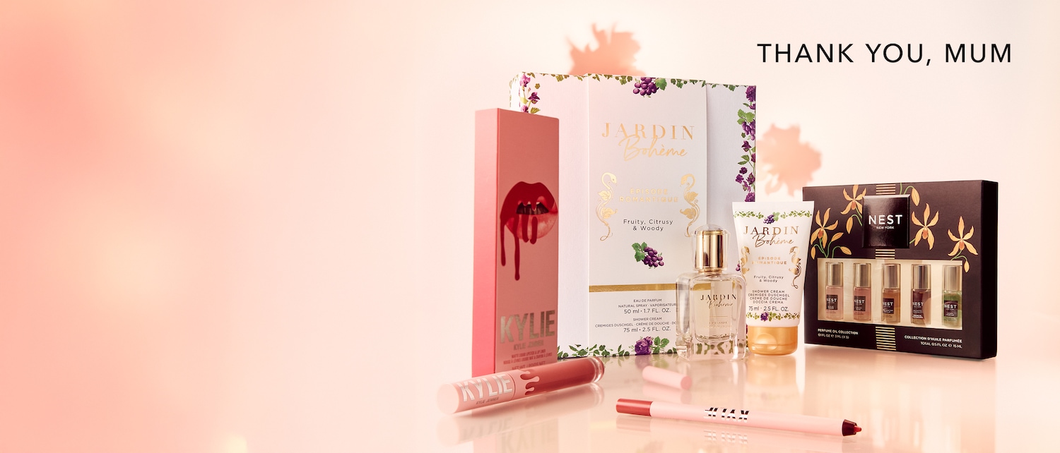 Eine Auswahl an Beauty-Produkten, darunter Kylie Cosmetics Lippenstifte und Jardin Bohème Parfums, präsentiert in sanften Rosa- und Goldtönen, ideal als Geschenk zum Muttertag.