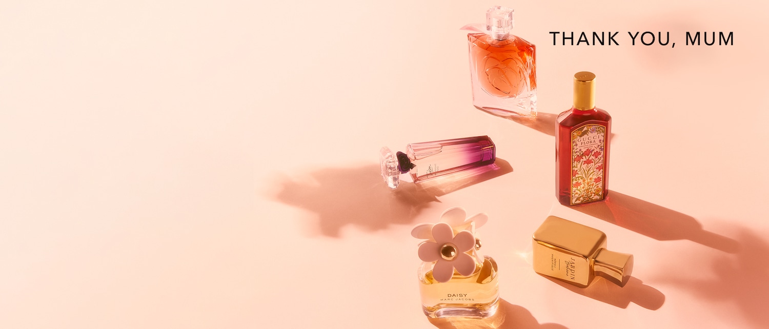 Auf hellrosa Hintergrund sind verschiedene Parfümflaschen zu sehen, darunter Daisy von Marc Jacobs und Gucci Flora, mit dem Text "Danke, Mama".
