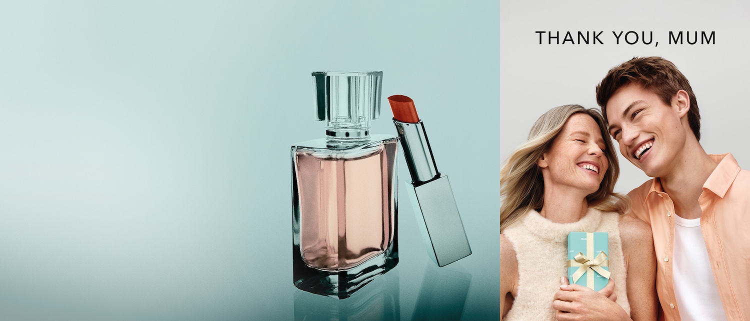 Ein elegantes Stillleben zeigt einen Parfümflakon mit klarem Verschluss und einen silbernen Lippenstift mit roter Spitze, während rechts ein lächelndes Mutter-Sohn-Paar mit einer hellblauen Geschenkbox zu sehen ist, darüber steht „DANKE, MAMA“.