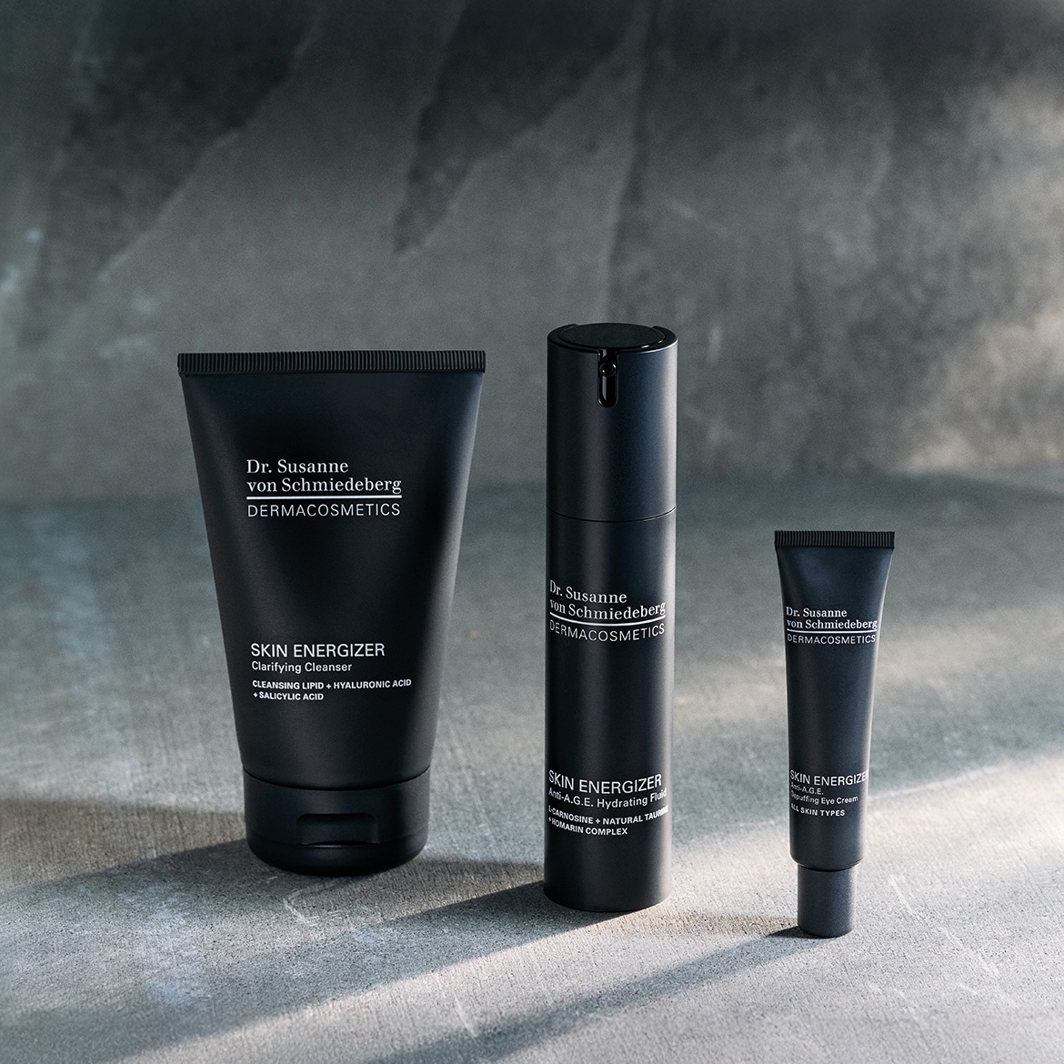 Drei schwarze Hautpflegeprodukte von Dr. Susanne von Schmiedeberg DERMACOSMETICS, darunter ein klärendes Reinigungsmittel, eine feuchtigkeitsspendende Flüssigkeit und eine Anti-Age-Augencreme.