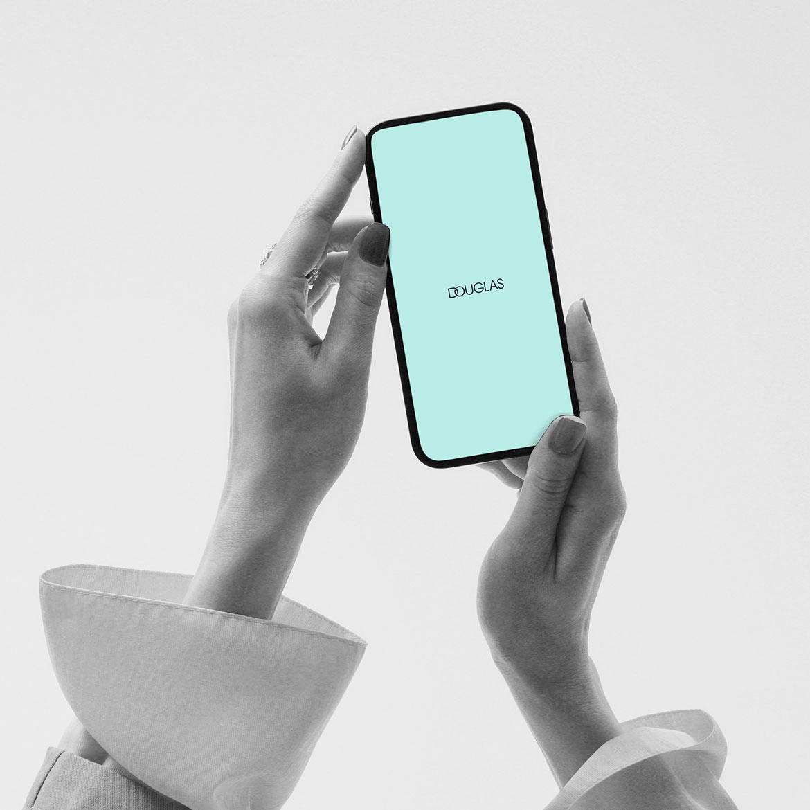 Ein Smartphone mit dem Douglas-Logo wird von zwei Händen gehalten, der Bildschirm ist hellblau.