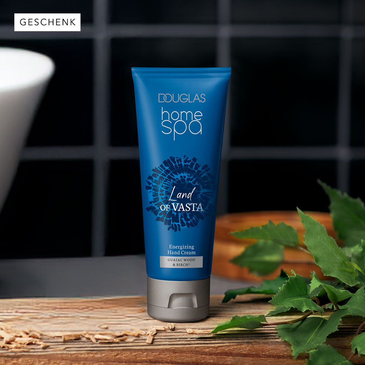 Die Douglas Home Spa Land Of Vasta Handcreme in blau-silberner Tube mit dem Schriftzug "Energizing Hand Cream Guaiac Wood & Birch" sorgt für ein entspannendes Spa-Erlebnis zu Hause.