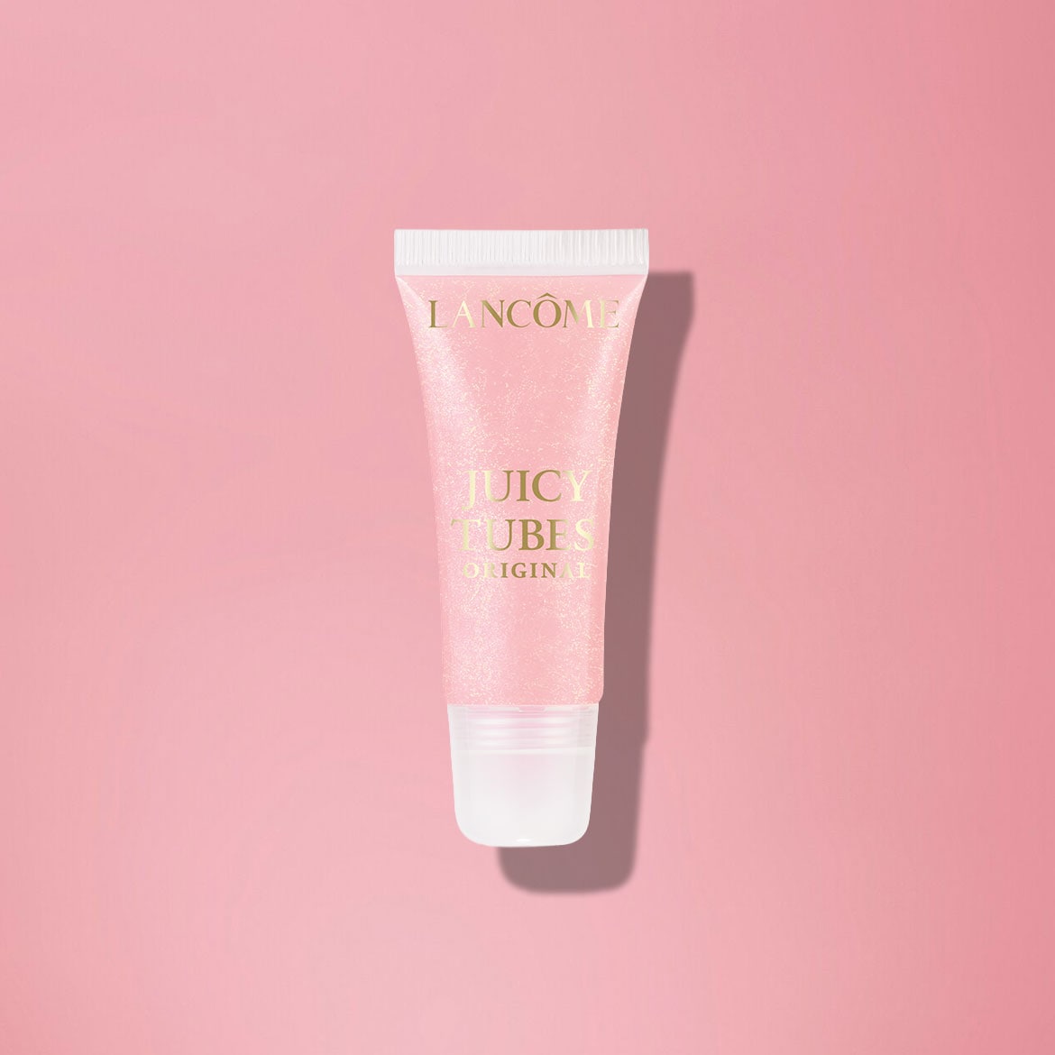 Nahaufnahme einer Tube Lancôme Juicy Tubes Original Lipgloss mit rosa schimmernder Textur und goldener Schrift auf rosafarbenem Hintergrund.