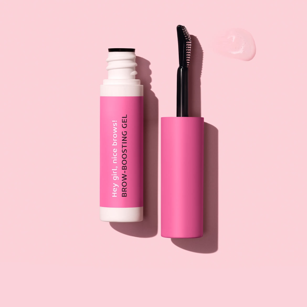 Auf hellrosa Hintergrund liegen eine geöffnete, weiße Tube mit pinkfarbener Banderole und schwarzer Schrift Hey girl, nice brows! BROW-BOOSTING GEL, sowie die pinkfarbene Bürste und ein Gel-Tropfen.