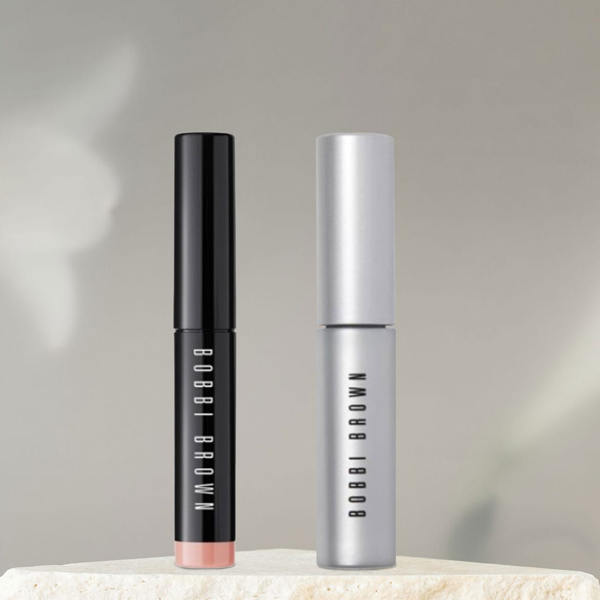 Zwei Bobbi Brown Lippenstifte, einer in glänzendem Schwarz mit einem Hauch von Pfirsich und der andere in schimmerndem Silber, versprechen einen Hauch von Eleganz für Ihr Make-up.