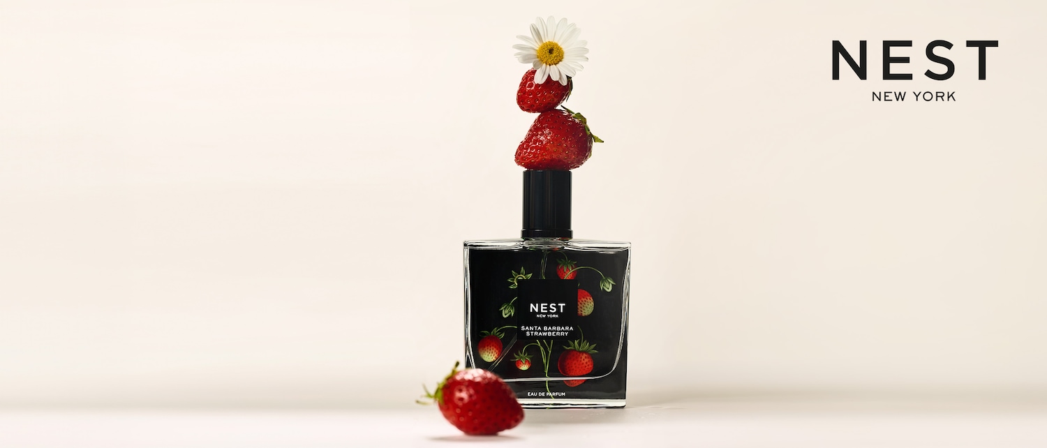 Entdecken Sie Nest New York Santa Barbara Strawberry Eau de Parfum, präsentiert in einer eleganten schwarzen Flasche mit Erdbeermotiven, gekrönt von frischen Erdbeeren und einer Gänseblümchenblüte.
