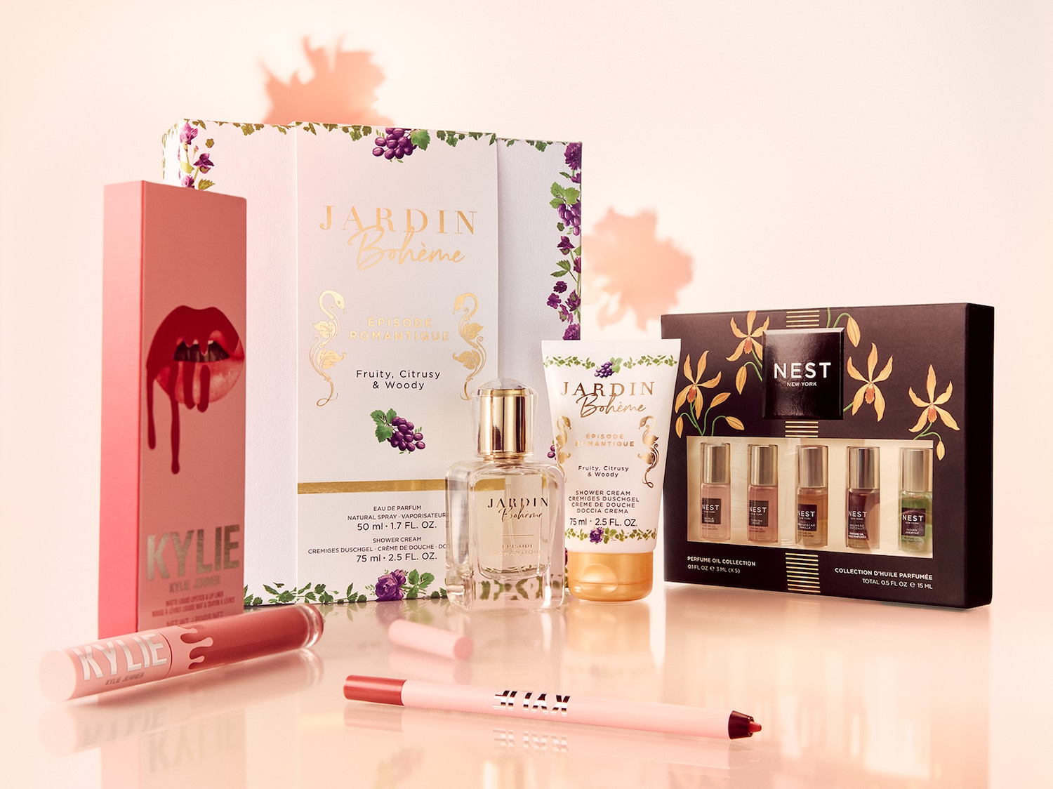 Eine Kollektion von Schönheitsprodukten, darunter Kylie Lippenstifte in rosa Verpackung, Jardin Bohème Düfte und Nest New York Parfümöl, die eine Mischung aus fruchtigen und holzigen Noten versprechen.