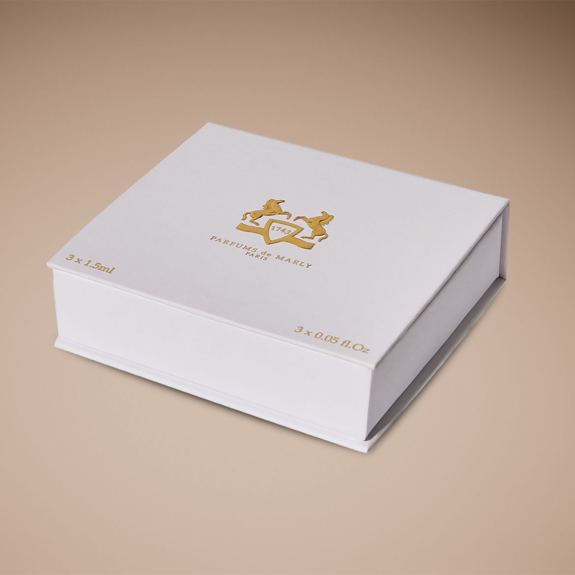 Weiße Parfum-Geschenkbox von Parfums de Marly mit goldenem Logo auf beigem Hintergrund.