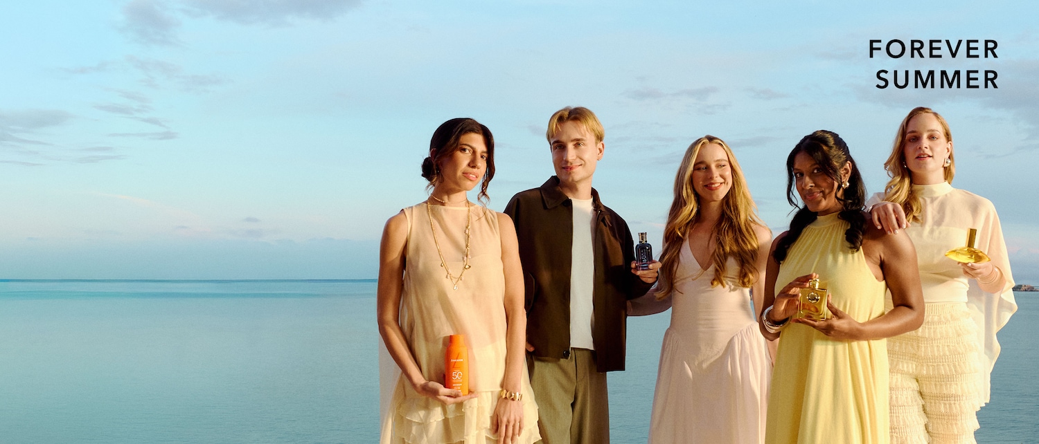 Fünf Personen mit Parfum- und Pflegeprodukten vor einer Küstenkulisse in sommerlicher Kleidung; unten steht „FOREVER SUMMER“.