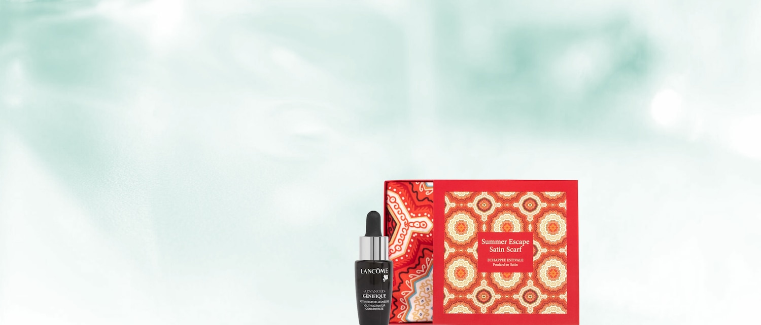 Das Lancôme Advanced Génifique Youth Activator Concentrate ist ein schwarzes Fläschchen mit Pipette, das neben einem roten Karton mit der Aufschrift "Summer Escape Satin Scarf" steht.