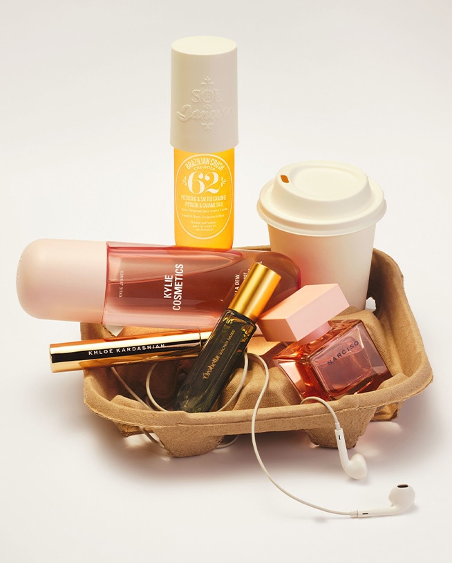 Verschiedene Beauty- und Pflegeprodukte, ein Coffee-to-go-Becher sowie Kopfhörer sind in einem Getränketräger arrangiert. Die Zusammenstellung steht für praktische Alltagsbegleiter und unkomplizierte Routinen für Schule, Studium oder Beruf.