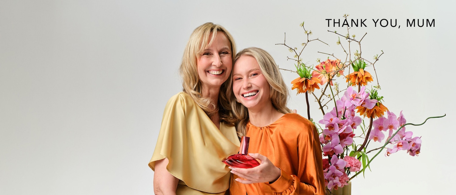 Ein strahlendes Mutter-Tochter-Duo, umrahmt von üppigen Blumen, feiert die Mutter mit dem Schriftzug "Thank You, Mum".