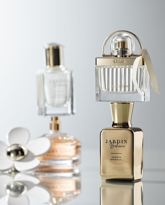 Verschiedene Parfümflaschen in Rot-, Rosa- und Türkistönen liegen übereinander und erzeugen ein schönes Farbspiel.