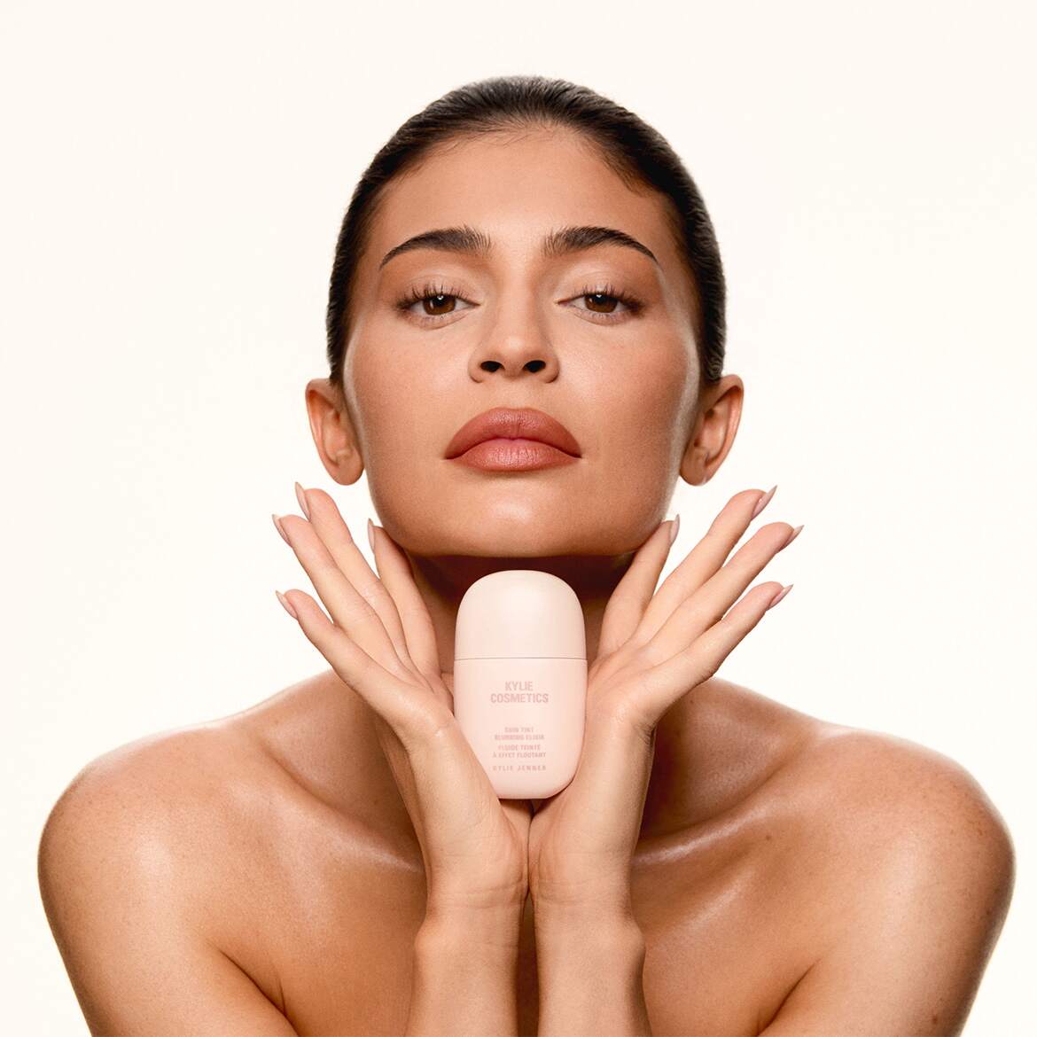 Kylie Jenner präsentiert das Skin Tint Balancing Serum von Kylie Cosmetics in einer hellrosa Flasche, das für einen ebenmäßigen Teint und einen strahlenden Effekt sorgt.